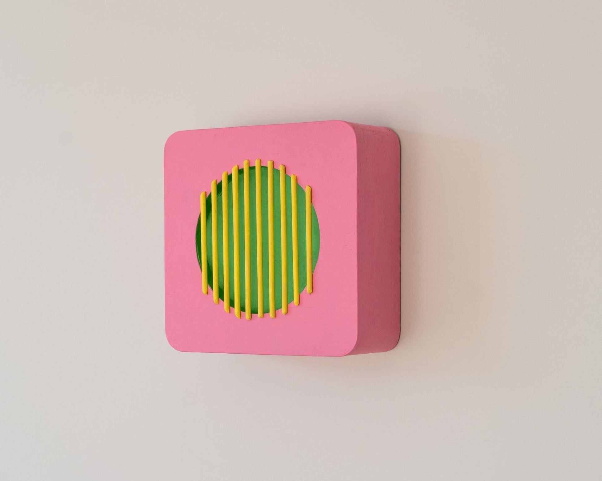 Modern wall sculpture in pink, green, and yellow with deep side profile, showing 3D geometric form inspired by vintage speaker design.