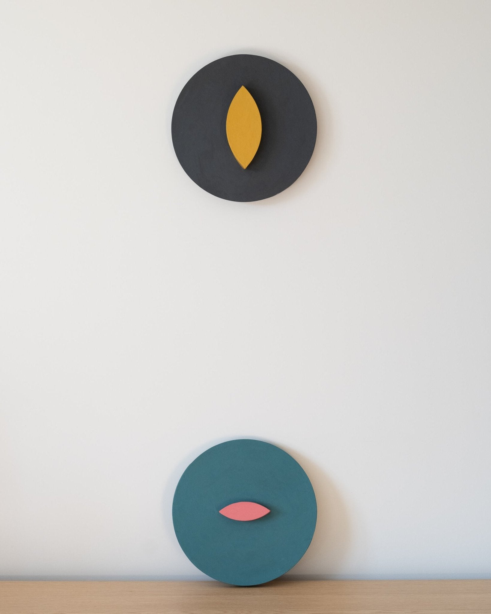Two circular wall art pieces with leaf designs on a light beige wall.