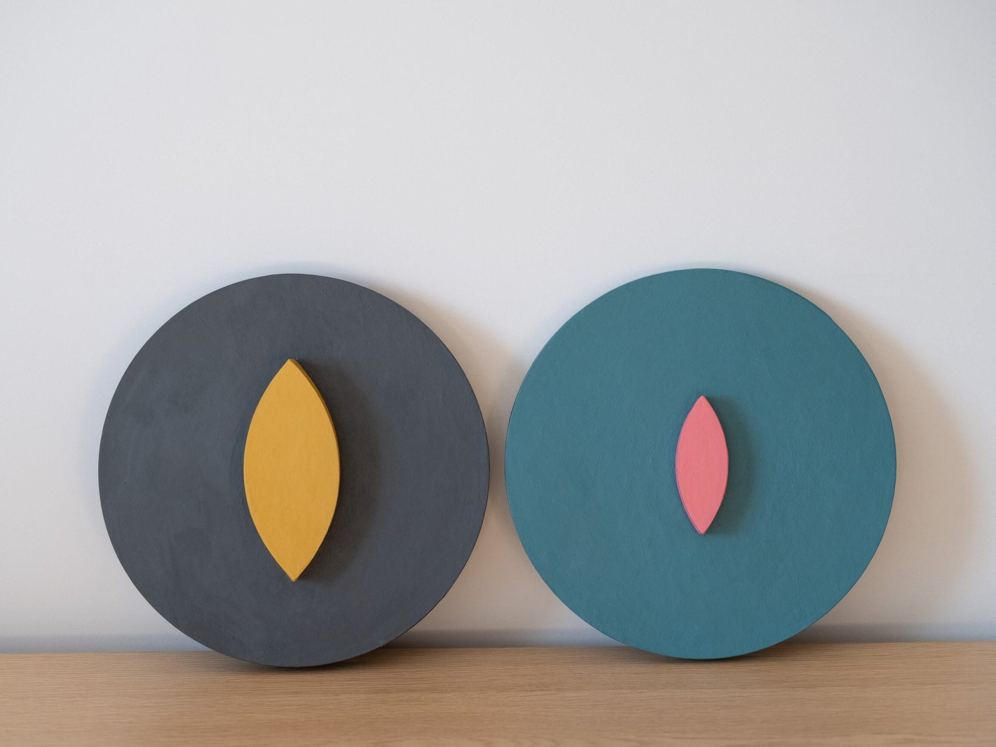 Two circular wall art pieces with leaf-shaped cutouts on a plain background