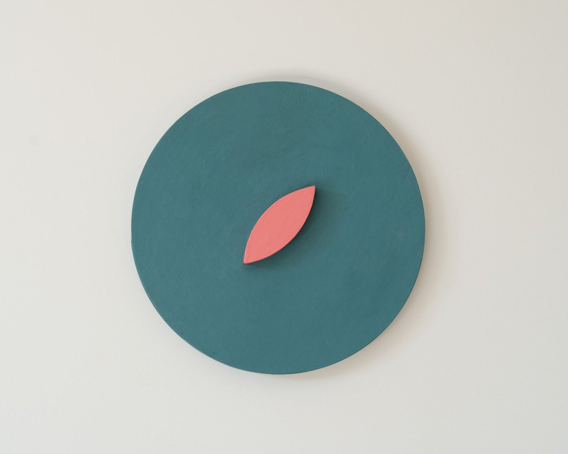 Teal circle with a pink leaf wall art on a light gray background
