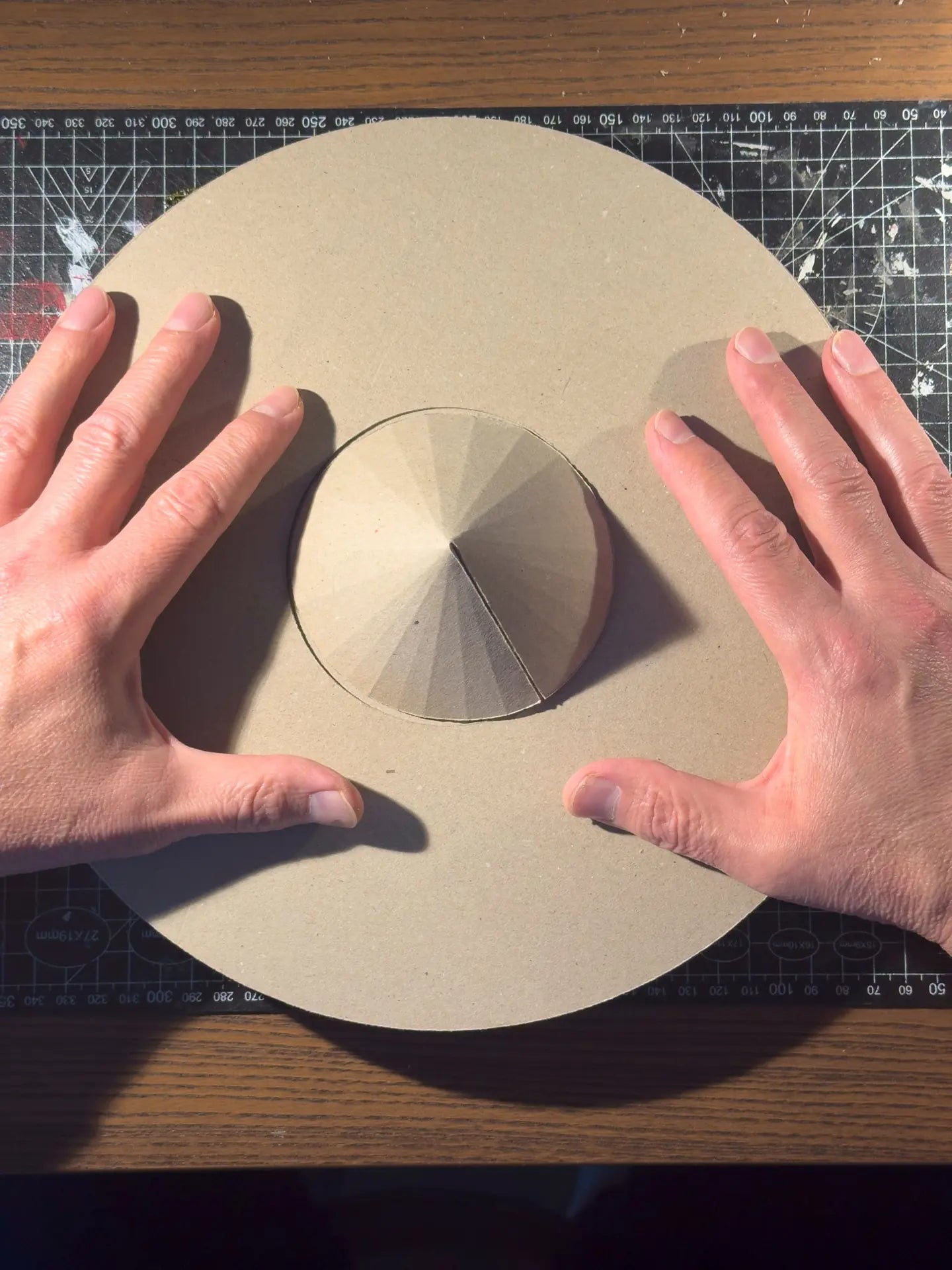Two hands fitting a cardboard cone into the centre of a round cardboard disc