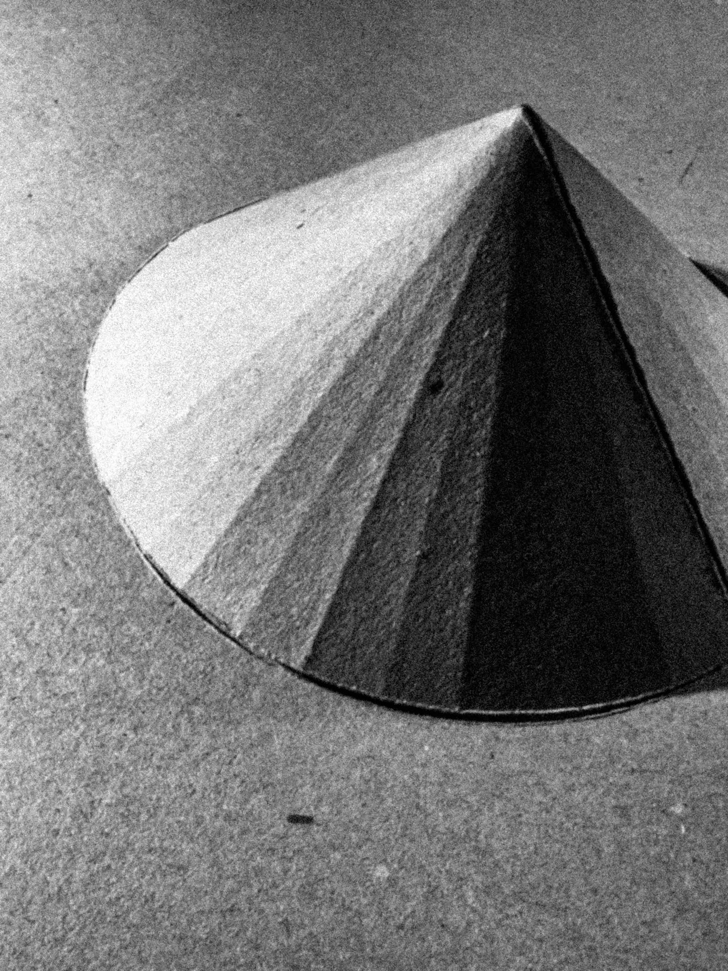 A cone folded from grey cardboard scored into narrow segments